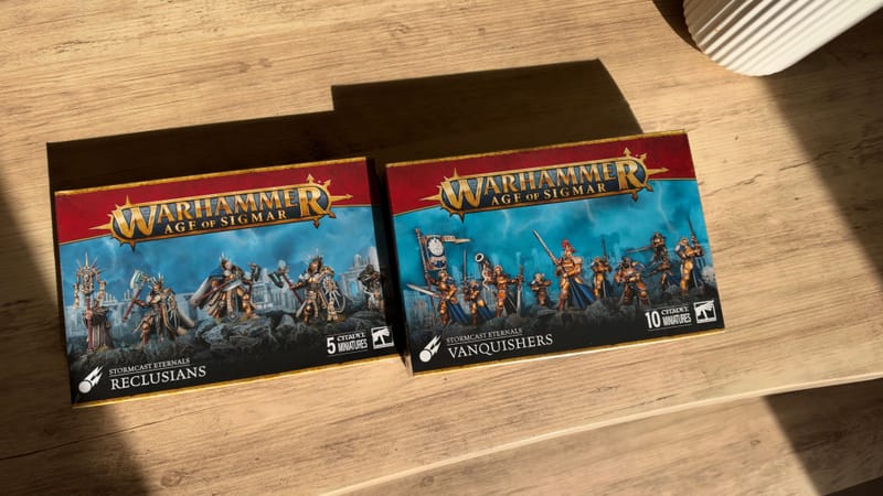 Two new Stormcast Eternals boxes on a wooden desk in the sun: Reclusians and Vanquishers.