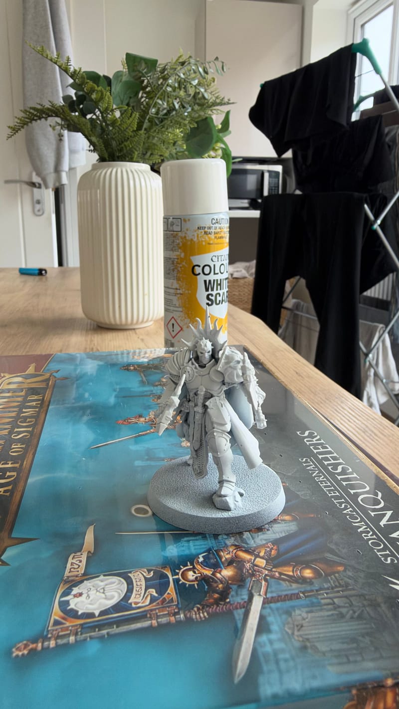 A primed Reclusian standing on its Vanquishers box lid, with a can of White Scar spray behind it.