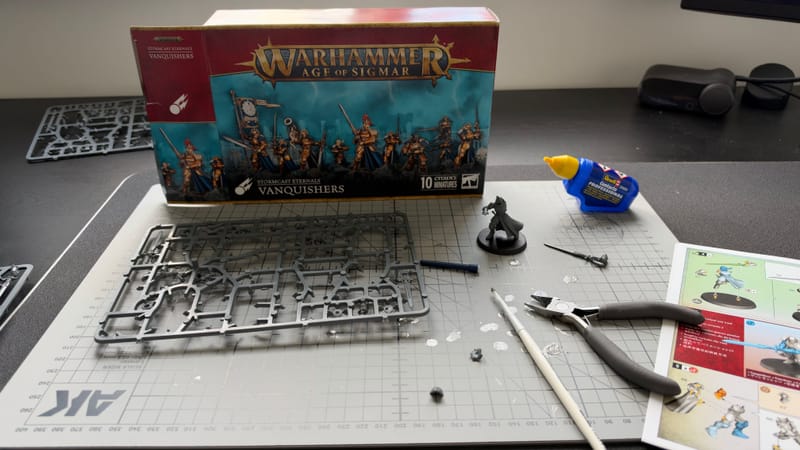A Vanquisher being built on a cutting mat, with the Vanquishers box, a sprue and hobby tools around it.