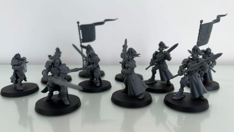 A closer look at the ten built Vanquishers, two of them holding banners, on a white table.